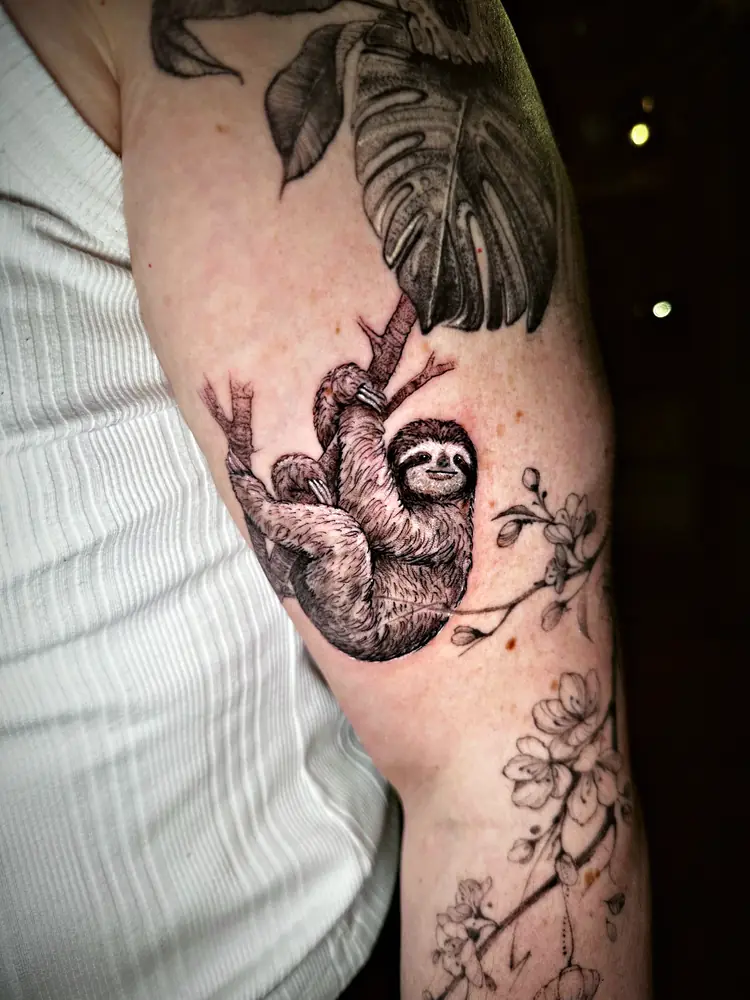 Sloth on a branch with monstera leaves tattoo by Damián Calandra