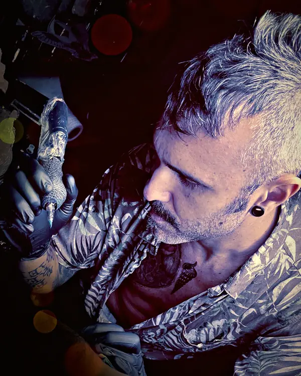 Damián tattooing under blue light